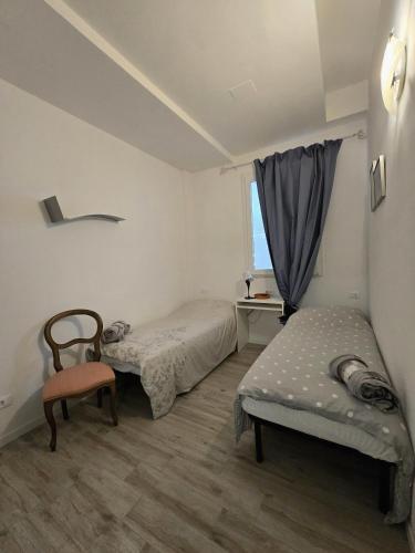 a bedroom with two beds and a chair and a window at La Casina in Follonica