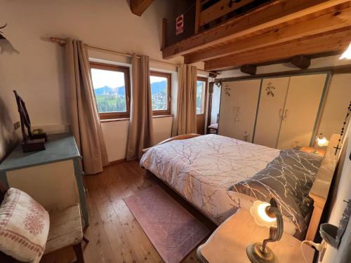une chambre avec un lit, une table et des fenêtres dans l'établissement Maso Pallabazzer - Colle Santa Lucia, à Colle Santa Lucia