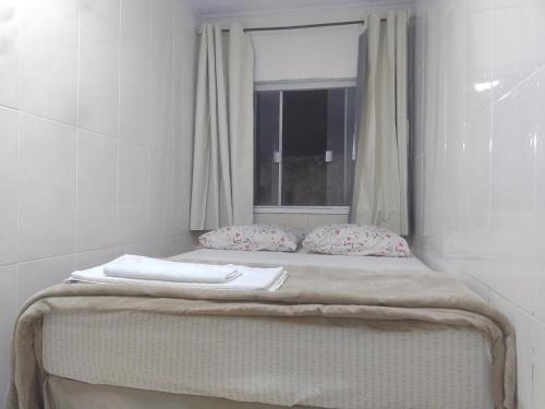 a bed with two pillows and a window at kitnet 01 preço popular in Brasília