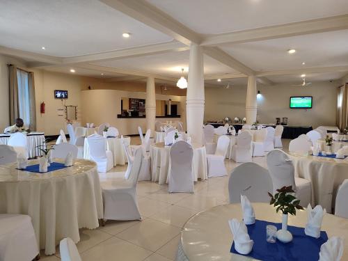a banquet hall with white tables and chairs at Garden Courts Hotel Masaka in Masaka
