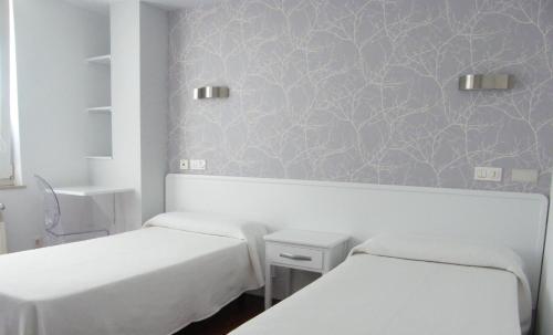 2 camas en una habitación con papel pintado púrpura en Hostal Valadares, en Noia