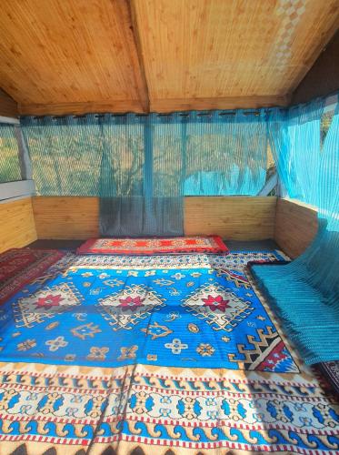 a bed with a blue comforter in a room at Mudhouse Cottage in Apple Orchard - Sainj Valley in Sainj