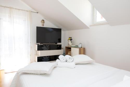 a white bedroom with a bed with two towels at Apartment Dome in Split