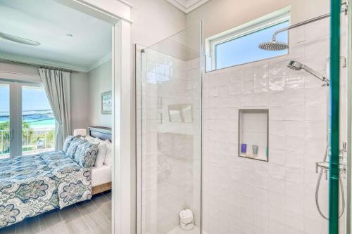 パナマ・シティ・ビーチにあるThe Sundownerのバスルーム(シャワー付)、ベッド1台、窓が備わります。