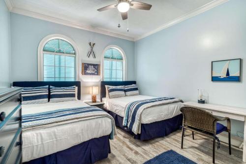 two beds in a room with blue walls and windows at Sandy's Seacrest in Inlet Beach