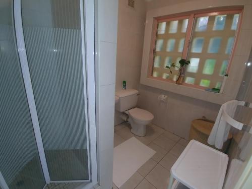 a bathroom with a toilet and a glass shower at The Green Gate in Zinkwazi Beach