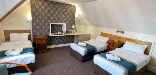 a hotel room with three beds and a mirror at Russell Hotel in Royal Tunbridge Wells