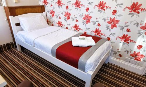 a small bedroom with a bed with red flowers on the wall at Russell Hotel in Royal Tunbridge Wells
