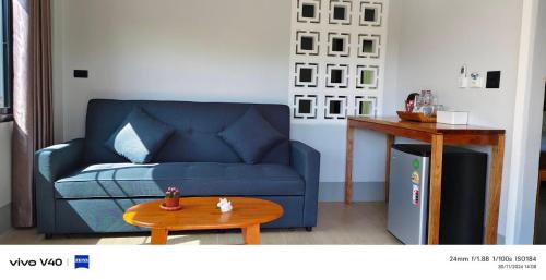 a living room with a blue couch and a table at Mookies Bungalows in Koh Mook