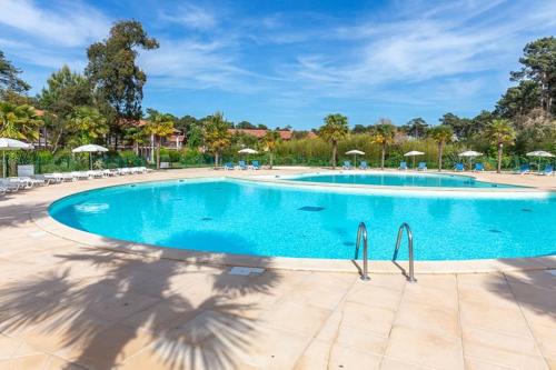 une grande piscine avec chaises et parasols dans l'établissement T2 tout équipé avec piscine sur côte océane, à Ondres