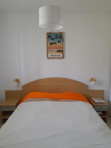 - une chambre avec un lit avec une couverture orange et 2 tables dans l'établissement T2 tout équipé avec piscine sur côte océane, à Ondres