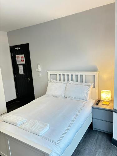 a bed with white sheets and pillows in a room at Southall Edge Inn in Southall
