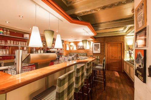 a bar in a restaurant with a row of chairs at Alpenhotel Tirolerhof in Fulpmes