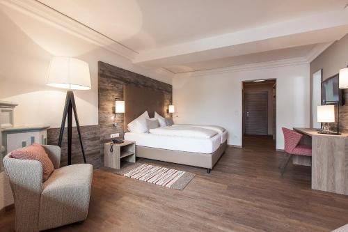 a bedroom with a bed and a couch and a chair at Alpenhotel Tirolerhof in Fulpmes