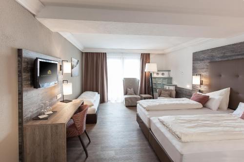 a hotel room with two beds and a television at Alpenhotel Tirolerhof in Fulpmes