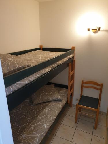 une chambre avec un lit superposé et une chaise dans l'établissement Cosy skis aux pieds, à Briançon
