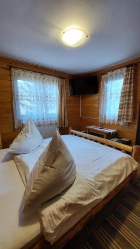 a bedroom with a large bed with white sheets and pillows at Cabana Dochita 2 in Ceahlău