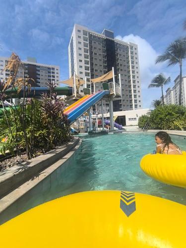 a woman in a pool with a slide in the water at Salinas Exclusive Resort in Salinópolis