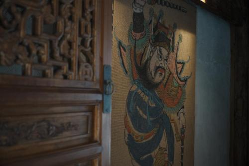 a painting of a woman on a wall next to a door at Ancient Charm Inn Chengdu in Chengdu