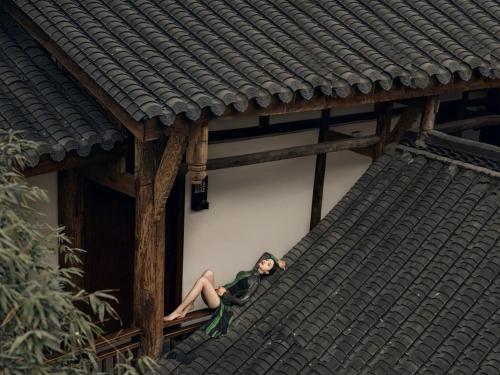 a woman sitting on the ledge of a building at Ancient Charm Inn Chengdu in Chengdu