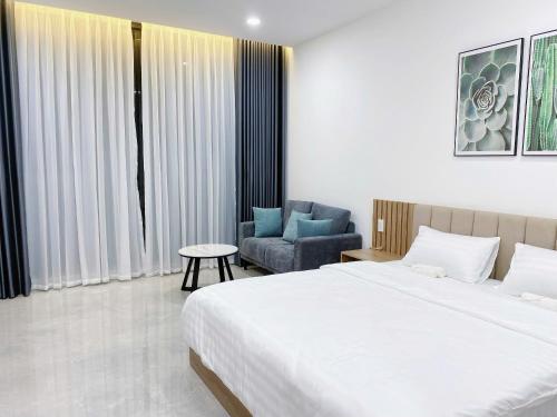 a bedroom with a large bed and a chair at DOME APARTMENT in Nhơn Trạch