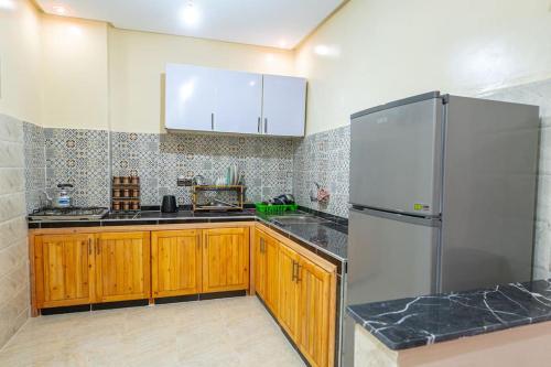 a kitchen with wooden cabinets and a stainless steel refrigerator at Bab Atas appartment N4 in Ourika Valley in Marrakech
