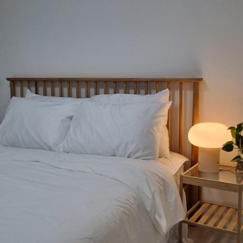 a bed with white sheets and a table with a lamp at 정스테이 서울 잠실 롯데월드 kspodome 아산병원 길동 코엑스 성수명동강남동대문 in Seoul