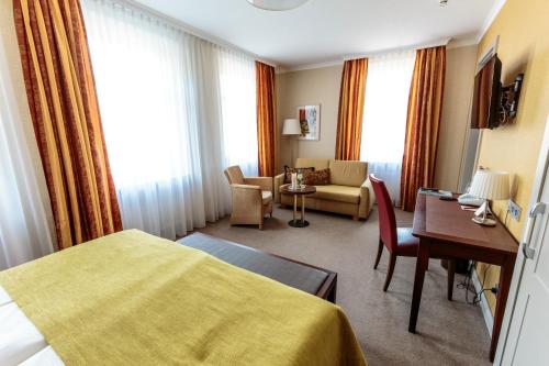a hotel room with a bed and a living room at Parkhotel Güldene Berge in Weißenfels