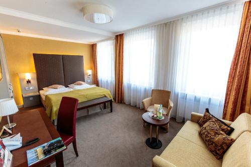 a hotel room with a bed and a couch at Parkhotel Güldene Berge in Weißenfels