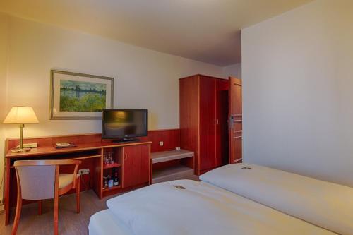 a hotel room with a bed and a desk with a television at Hotel Fürsteneck in Bernburg