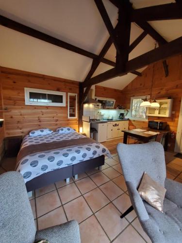 a bedroom with a bed and two chairs at Cabane des bois in Rouffignac Saint-Cernin