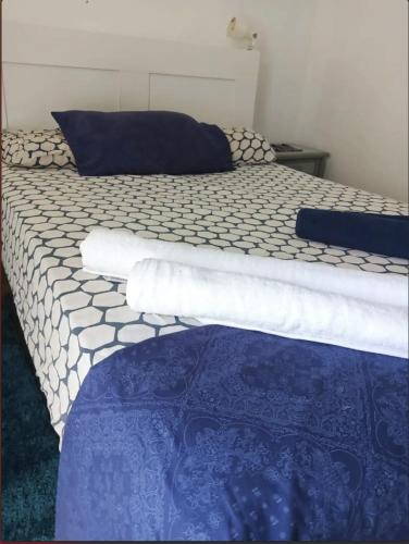 a bed with white sheets and blue and white comforter at Magic view facing MontanaRoja in La Tejita