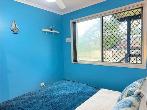 a blue bedroom with a bed and a window at Heaven on Earth in Kingston