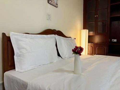a white vase with a flower in it on a bed at Apamet Hotel Sukhumvit 55 in Khlong Toei