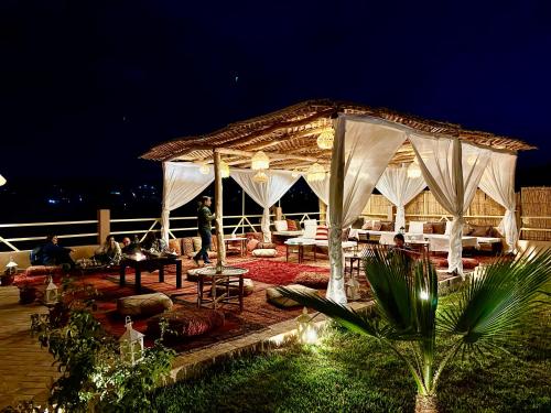 a pavilion with people sitting under it at night at Riad Sahara Stars Dades in Boumalne