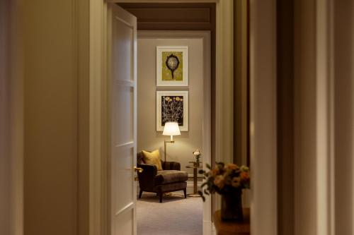 a hallway with a living room with a chair and a clock at Corinthia Grand Hotel Astoria Brussels in Brussels