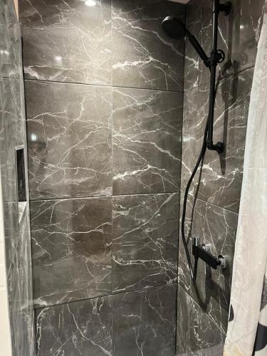 a bathroom with a shower with a gray marble wall at Trois-Épis, vue magnifique in Ammerschwihr