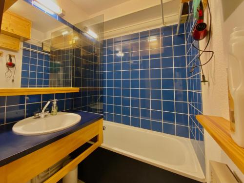 une salle de bain carrelée bleue avec un lavabo et une baignoire dans l'établissement Studio cosy au cœur de Samoëns, proche commerces et ski bus, balcon, parking, animaux acceptés - FR-1-624-157, à Samoëns