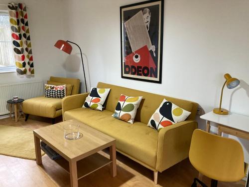 a living room with a yellow couch and a table at Blaengwen Bach in Pencader
