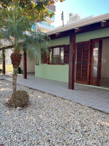 una casa con una palmera delante en Casa Maré de Bombas - em Pousada Maré de Bombas, en Bombinhas