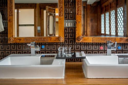 two sinks in a bathroom with two mirrors at Walk Together Hotel in Lijiang