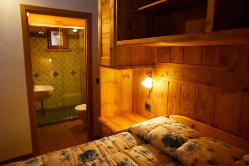 a bedroom with a bed and a bathroom with a sink at Le Nid de l'Aigle in Champoluc