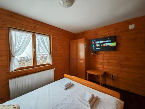 a bedroom with a bed and a tv on the wall at Alpine Escape Studios in Măgura
