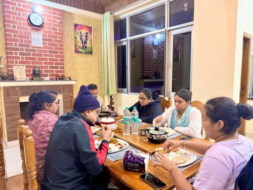 a group of people sitting at a table eating food at The Auriga 3BHK Fully Entair Villa with Bonfire in kasauli I Pvt Stay I Open Air Terrace I Kitchen Livingroom I Lawn Bonfire I Gaming Zone in Kasauli