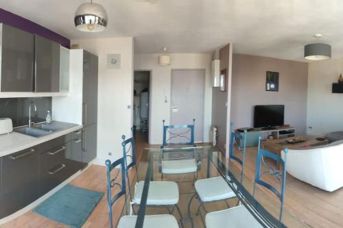 une cuisine avec une table en verre et des chaises dans une pièce dans l'établissement Grand T2 lumineux avec parking, à Nantes