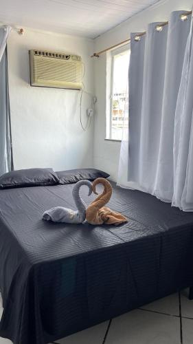 two swans are sitting on a bed at Cantinho do sossego Arraial do cabo - Prainha in Arraial do Cabo