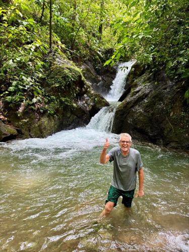 a man standing in the water in front of a waterfall at Ceiba Ganadito in Drake