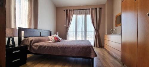 a bedroom with a bed and a large window at Shanti Paphos Holiday House in Paphos City