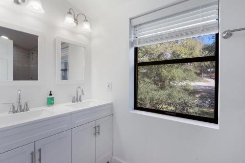 a white bathroom with two sinks and a window at Wimberley Log Cabins Resort and Suites- Unit 3 in Wimberley