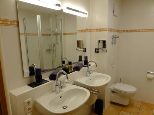 a bathroom with two sinks and a toilet and a mirror at Boutiqueferienwohnung Schnapshäusel in Oberstdorf